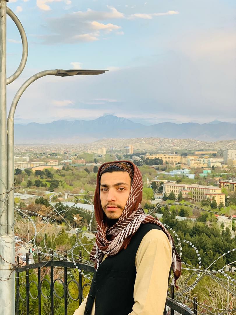 a person wearing a scarf and standing on a balcony overlooking a city